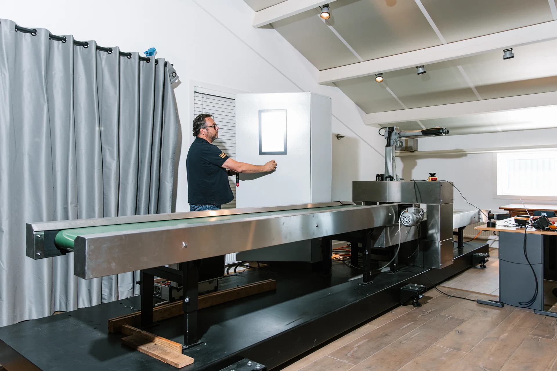 Machine control in a test setup with a conveyor and an engineer at the cabinet.