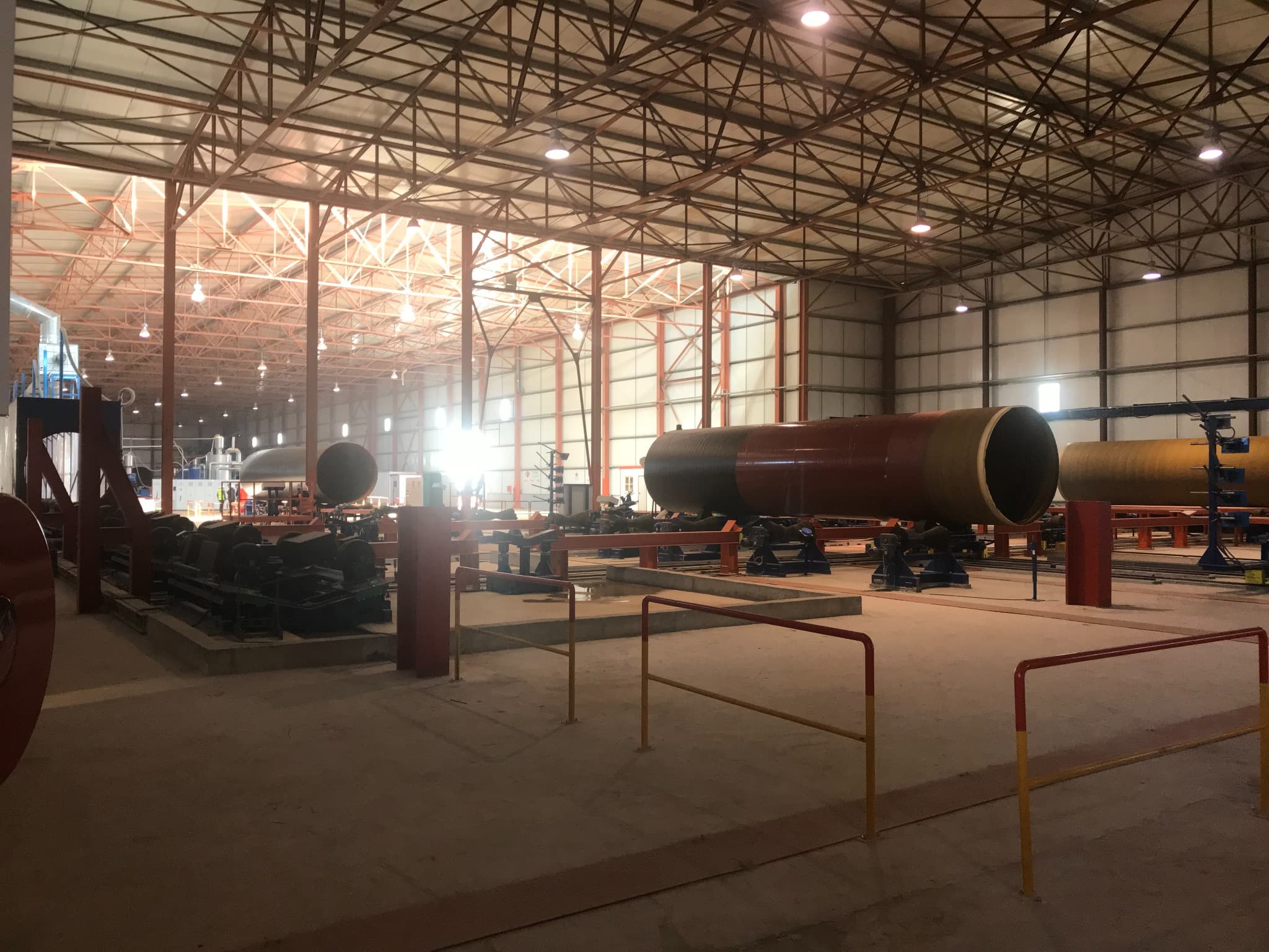 Production hall with large pipes on roller beds.