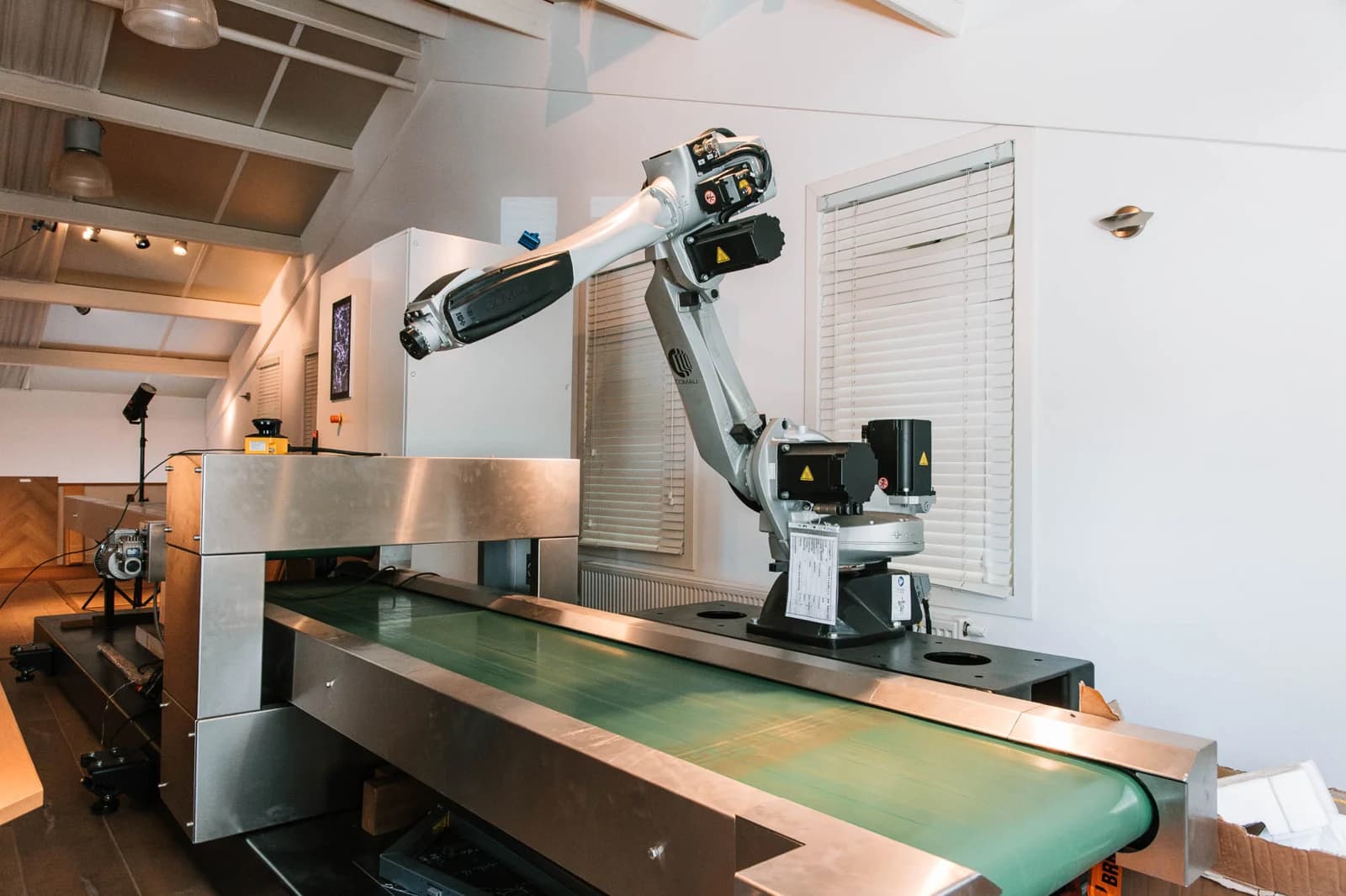 COMAU robot beside a conveyor at Blom Opmeer