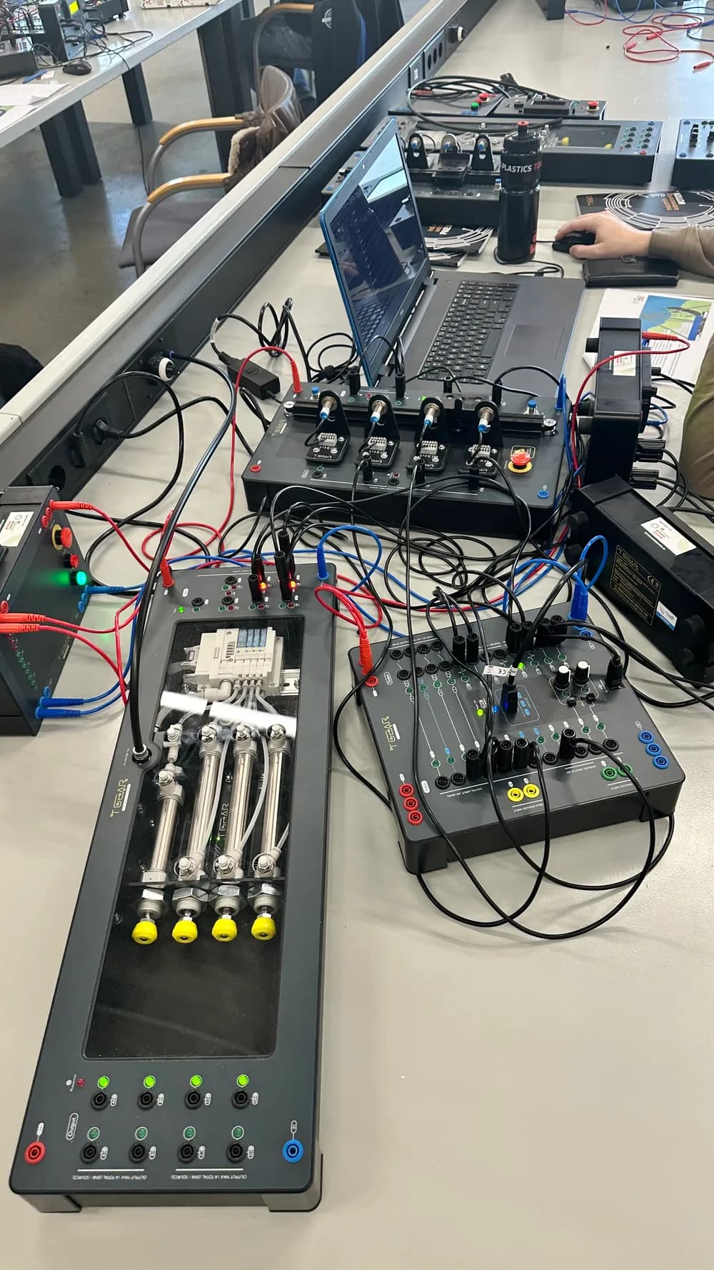 Training setup with pneumatic cylinders, control modules and a laptop at De Techniekschool, with no faces visible